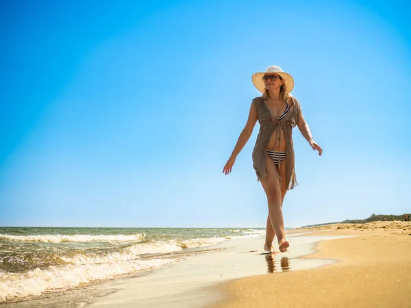 在阳光明媚的海滩上行走的女人 — 图库照片