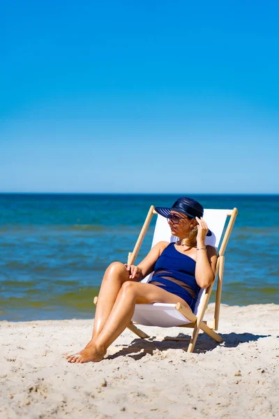 女人坐在沙滩上躺在日光浴床上休息 — 图库照片