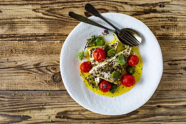 Roasted tomatoes with feta cheese and broad bean served on wooden table