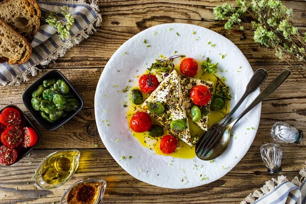 Roasted tomatoes with feta cheese and broad bean served on wooden table