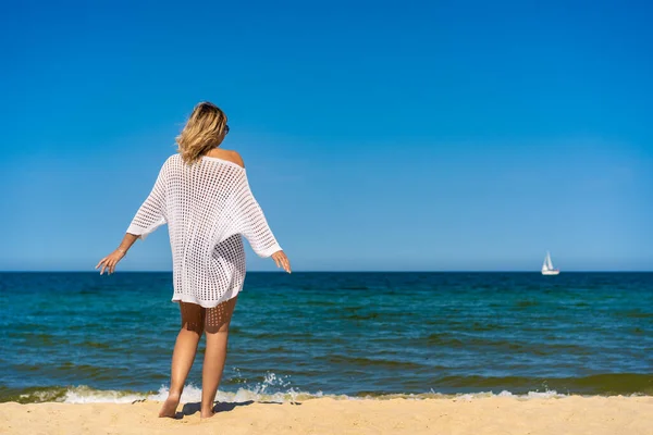 太陽が降り注ぐビーチの上を歩く女性 — ストック写真