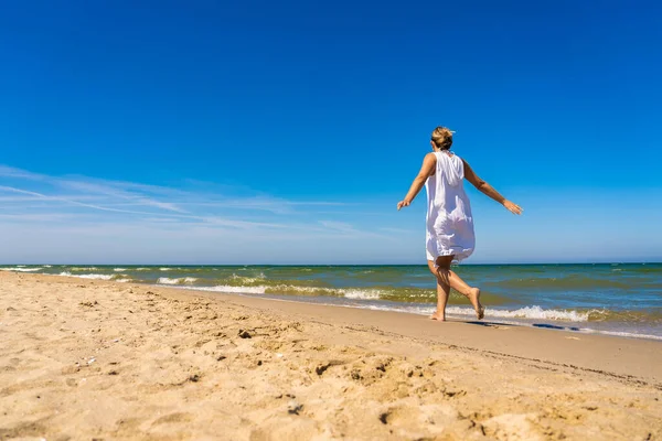 在阳光明媚的海滩上行走的女人 — 图库照片