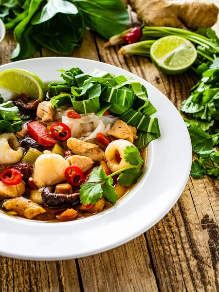 Yunnan hot pot - Chinese soup with chicken meat on wooden table