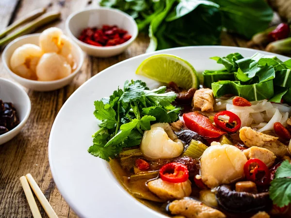 Yunnan hot pot - Chinese soup with chicken meat on wooden table