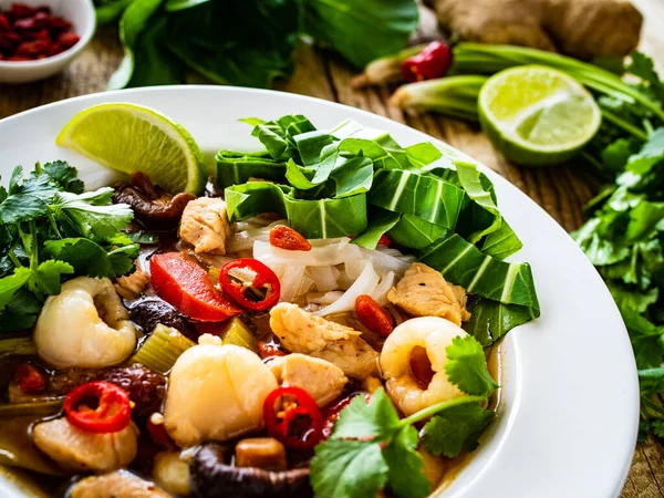 Yunnan hot pot - Chinese soup with chicken meat on wooden table