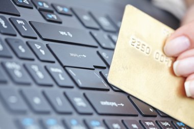 kredi kartı laptop üzerinde tutan kadın