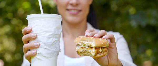 Женщина ест гамбургер и коктейль — стоковое фото