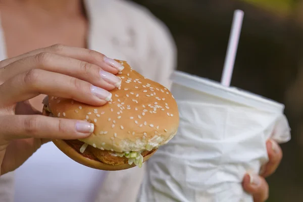 Žena jíst hamburger a koktejl — Stock fotografie
