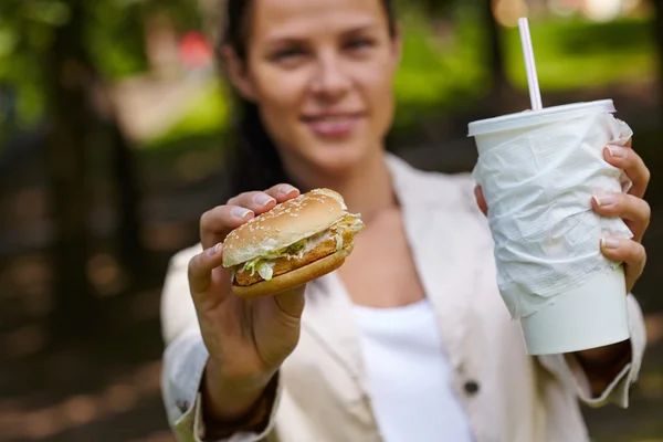 Žena jíst hamburger a koktejl — Stock fotografie