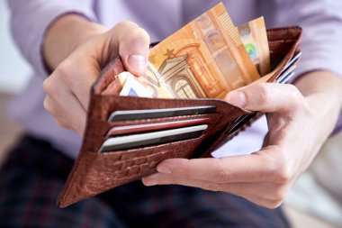 man putting money in wallet, closeup