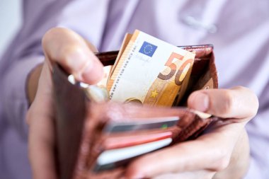 man putting money in wallet, closeup