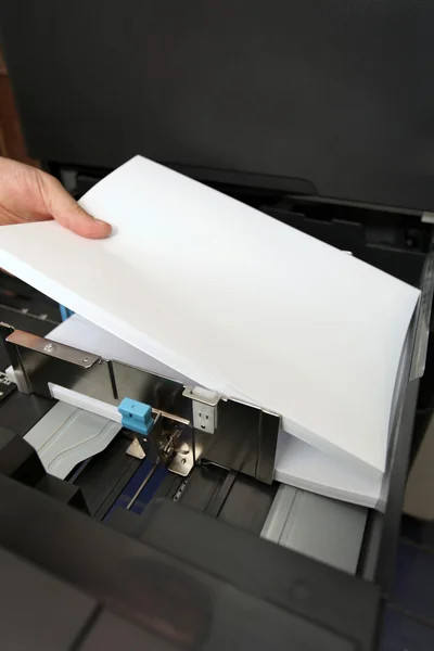 Details of hand inserts a paper A4 into a laser copier — Stock Photo, Image