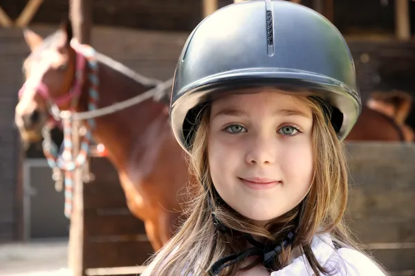 Klein meisje en bruin paard Stockfoto