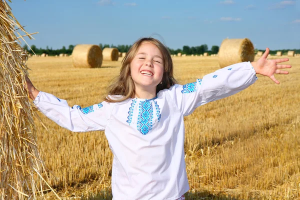 Petite fille rurale sur le champ de récolte avec des balles de paille — Photo