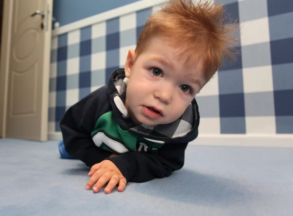 Ένα περίεργο μωρό αγόρι που βρίσκεται σε ένα πάτωμα στην αίθουσα — Φωτογραφία Αρχείου