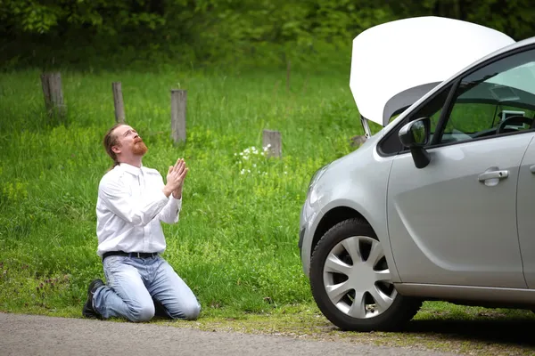 Funny driver praying a broken car by the road — Stock Photo, Image