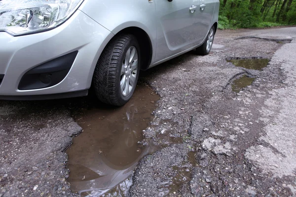 Route endommagée pleine de nids de poule fissurés dans la chaussée — Photo