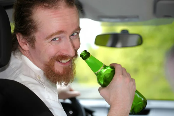 Dronken man in auto met een fles bier — Stockfoto