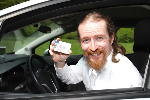 Conducente sorridente seduto in auto e mostrando la patente di guida — Foto Stock