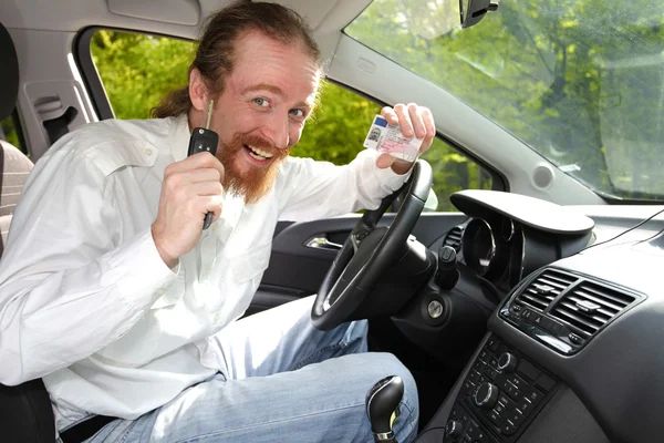 微笑着坐在车里，并显示新车钥匙和驱动器的驱动程序 — 图库照片
