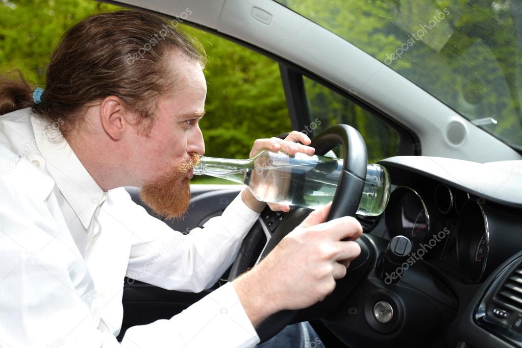 Drunk man in car with a bottle alcohol