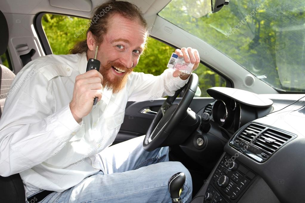 driver smiling sitting in car and showing new car keys and drive