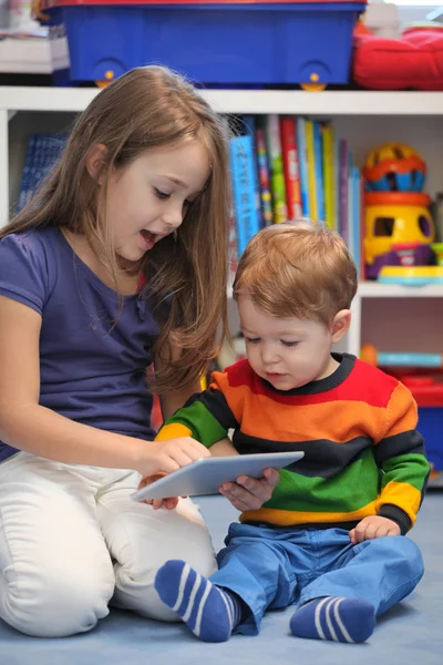 Dziewczyna z jej młodszy brat zabawy przy użyciu komputer typu tablet cyfrowy — Zdjęcie stockowe