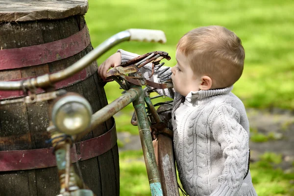 2 years old curious Baby boy walking around the old bike — Stock Photo, Image