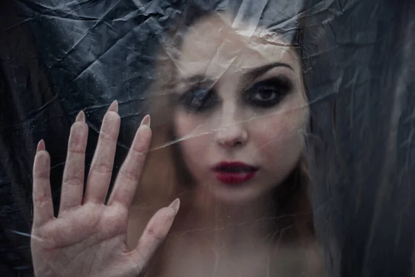 Young beauty sad woman trapped behind a plastic sheet as protection against COVID-19. Nicely fits for book cover