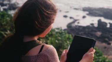Genç Asyalı kadın deniz kenarında, Hindistan ve Goa 'da otururken resim çizimi, resim tasarımı için dijital tablet kullanıyor. 