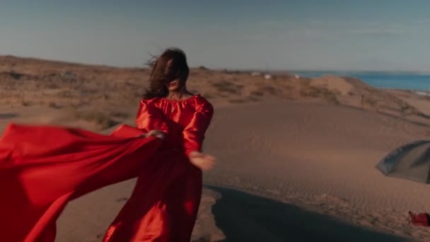 Una mujer asiática en un vestido rojo bailando en dunas de arena — Vídeos de Stock