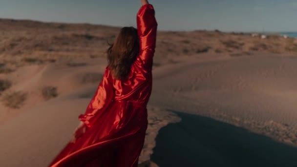 Een aziatische vrouw in een rode jurk dansen op zand duinen — Stockvideo
