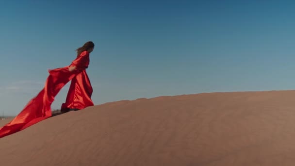 An Asian woman in a red dress dancing on sand dunes — Stock Video