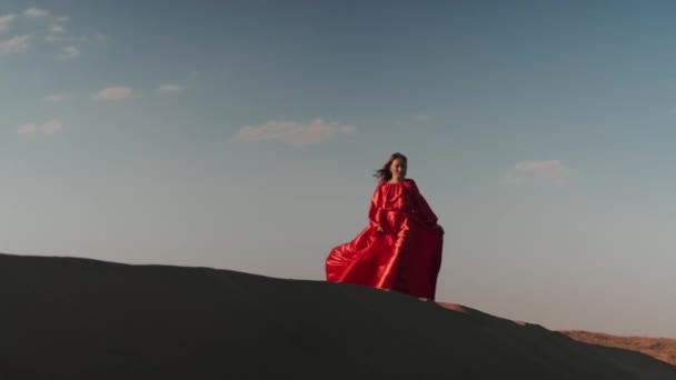 An Asian woman in a red dress dancing on sand dunes — Stock Video