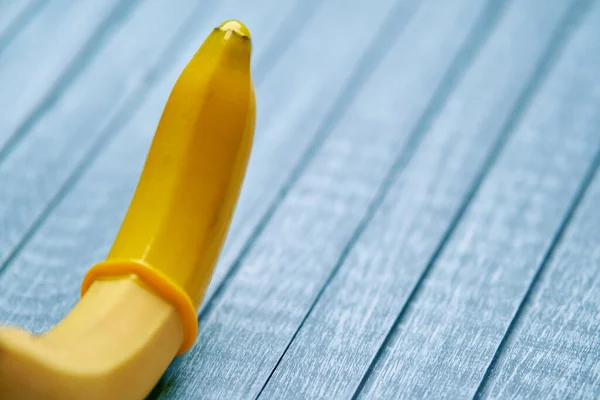 Žlutý Kondom Žlutý Banán Leží Modrém Dřevěném Pozadí — Stock fotografie