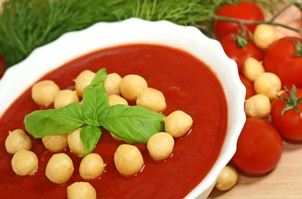 Closeup of bowl of tomato soup garnished with basil leaves — Stock Photo, Image