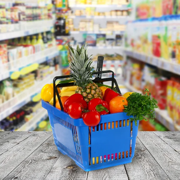 Cesto shopping con generi alimentari sul negozio di sfondo — Foto Stock