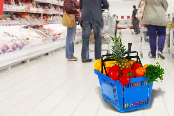 Cesto shopping con generi alimentari sul negozio di sfondo — Foto Stock