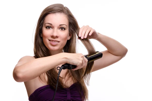 Smiling young woman straightening her hair Royalty Free Stock Photos