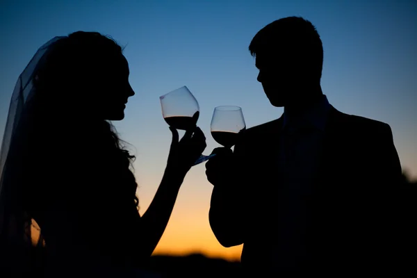 Bruid en bruidegom wijn te drinken bij zonsondergang — Stockfoto