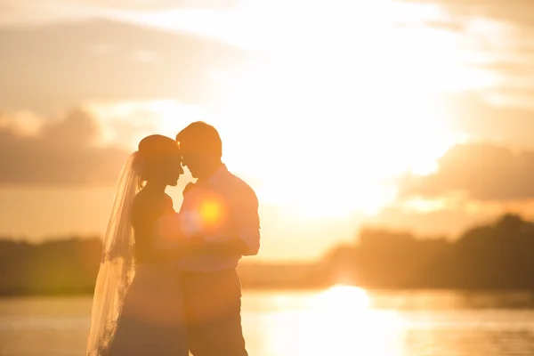 Świeżo poślubiona para nad rzeką z zachodu słońca — Zdjęcie stockowe