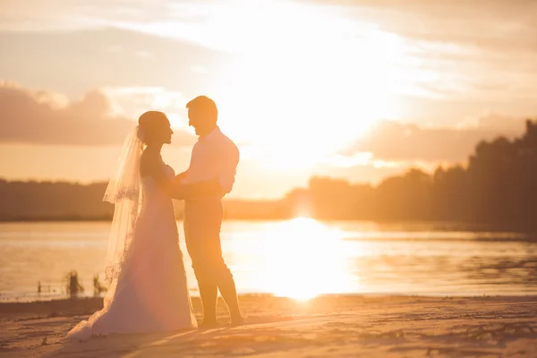 Coppia appena sposata sul fiume con tramonto — Foto Stock