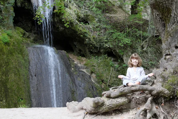 Little girl meditate by the waterfall — Stock Photo, Image