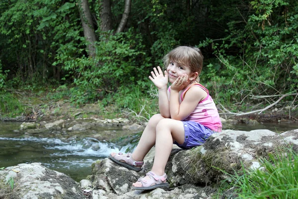 Menina sentada ao lado de um riacho — Fotografia de Stock
