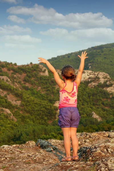 Little girl standing on mountain peak — Stock Photo, Image