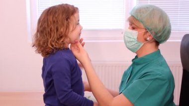 kadın doktor küçük kızın boğazını ele alıyor.