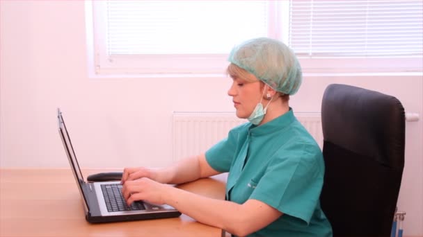 Female doctor typing on laptop and talking on phone — Stock Video