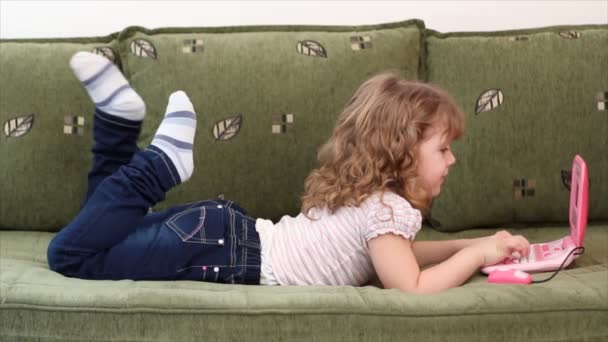 Niña acostada en la cama con portátil — Vídeos de Stock