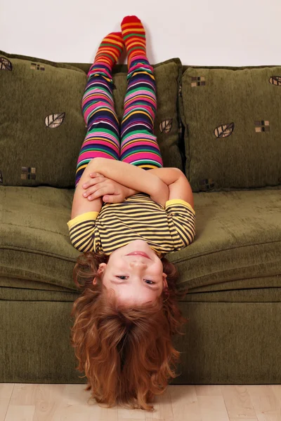 Little girl lying upside down on the bed — Stock Photo, Image