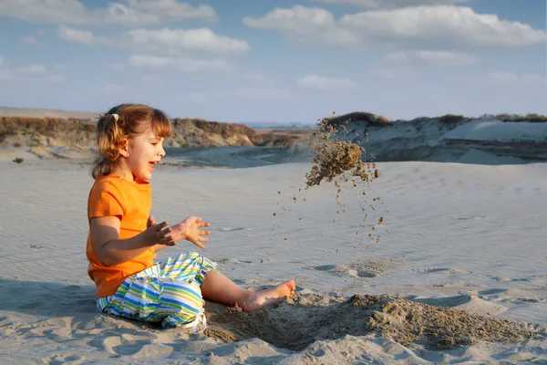 Menina feliz brincando na areia — Fotografia de Stock